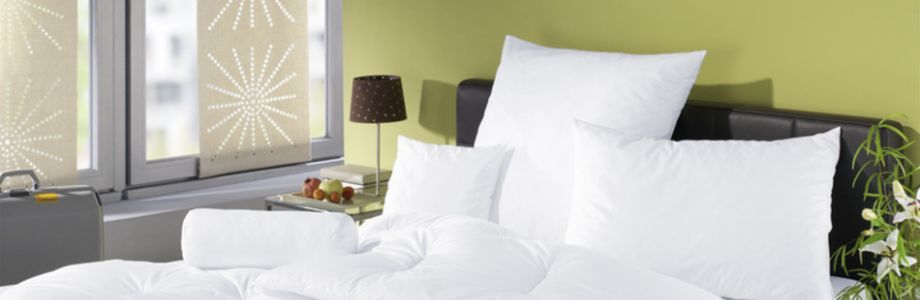 Hotelzimmer mit Bett und auf dem Bett liegen Hotelkissen